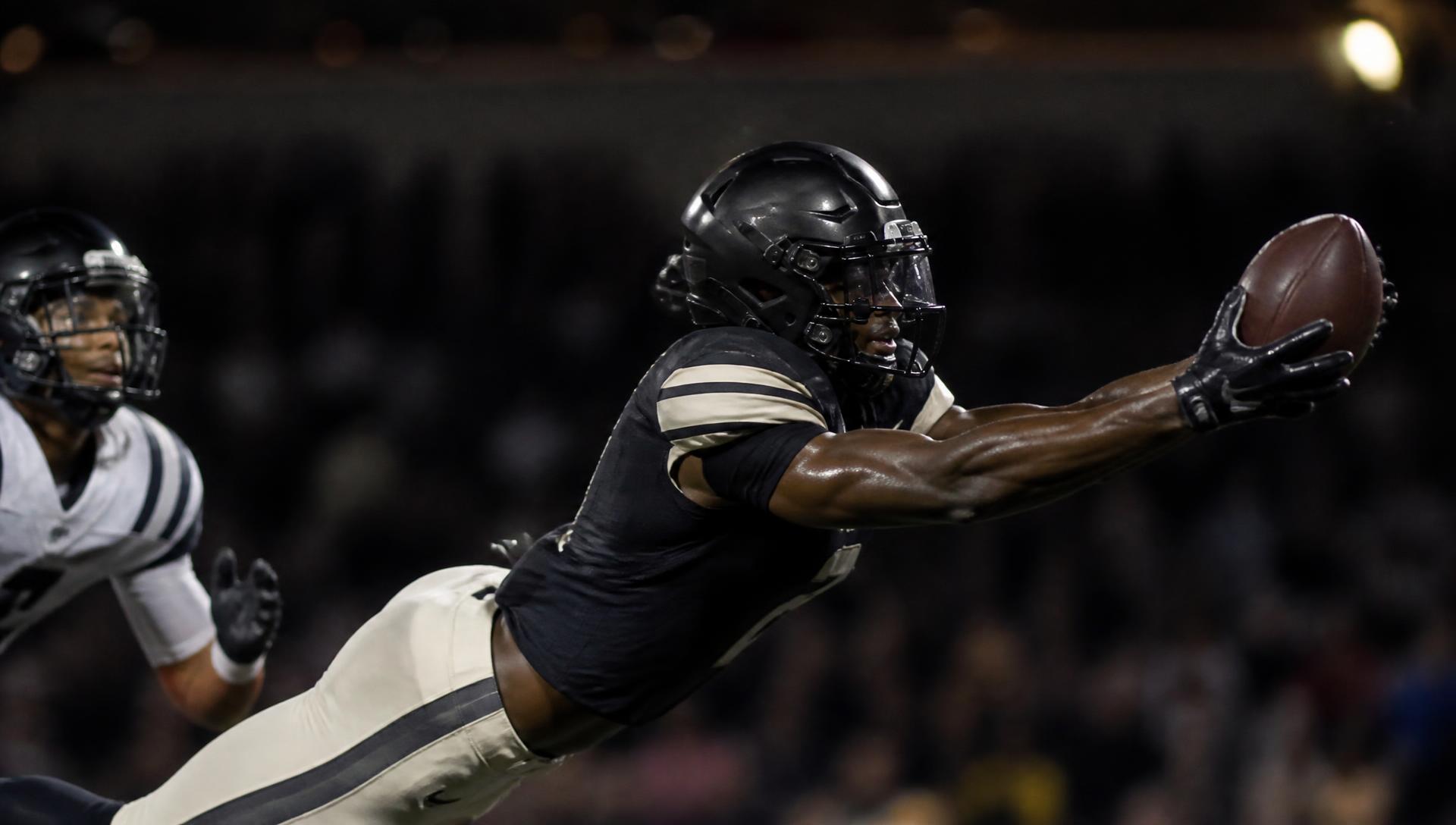 Long lens frame of a receiver catching a football at night